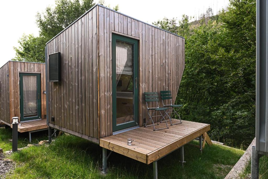 a small wooden house with a chair on a deck at Sleep Space 35 - Green Tiny Village Harz in Osterode