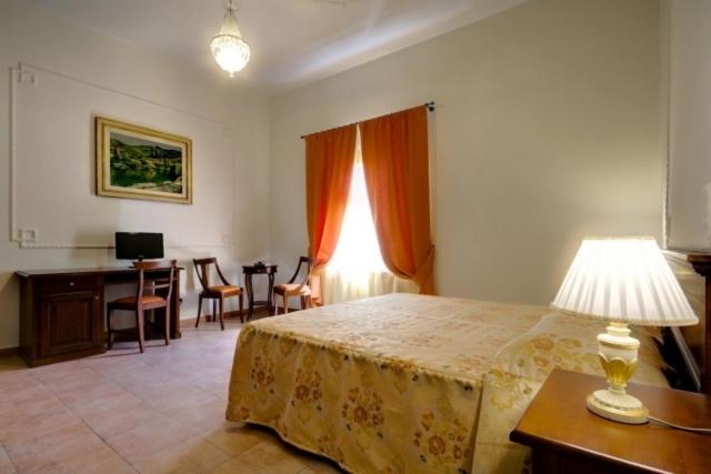 バルベリーノ・ディ・ムジェッロにあるHotel Il Cavalloのベッドルーム1室(ベッド1台、デスク、ランプ付きテーブル付)