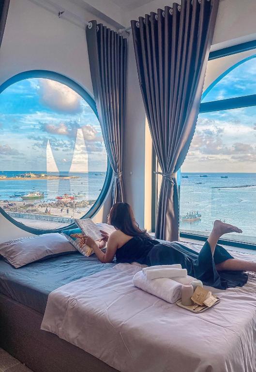 a woman laying on a bed with a view of the ocean at Dứa Homestay in Cu Lao Thu