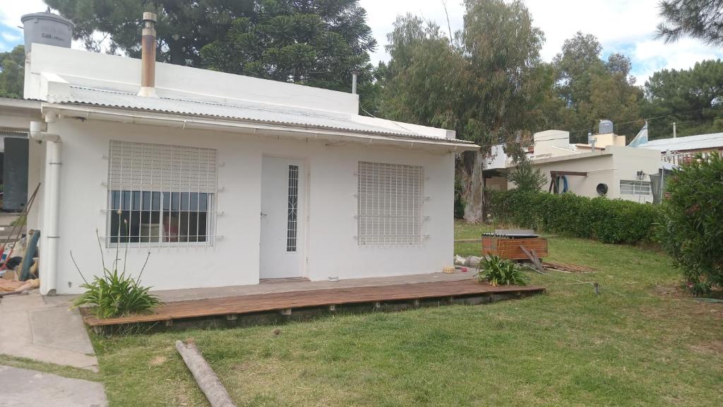 Casa blanca con porche de madera en un patio en Casa Las Dunas- 6 cuadras del mar, en Monte Hermoso