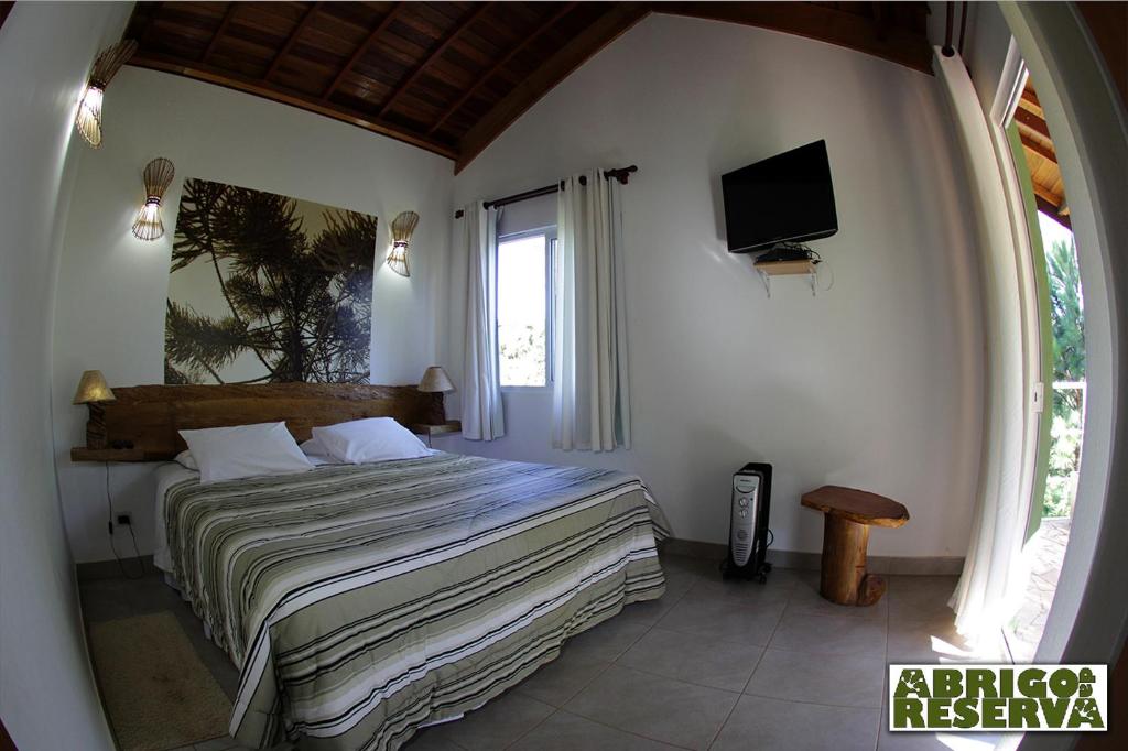 una camera da letto con un letto e una TV in una stanza di Abrigo da Reserva a Santo Antônio do Pinhal