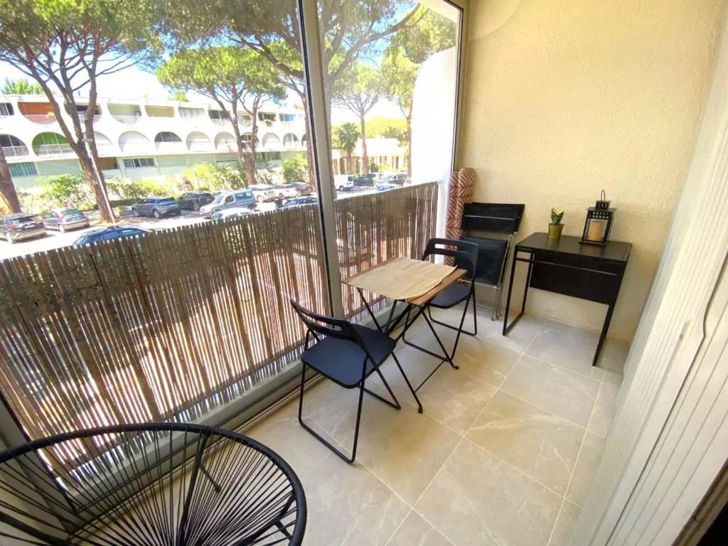 d'un balcon avec une table, des chaises et un bureau. dans l'établissement Studio Cabine Centre-Ville, Parking & Animaux Acceptés - FR-1-307-274, à La Grande Motte