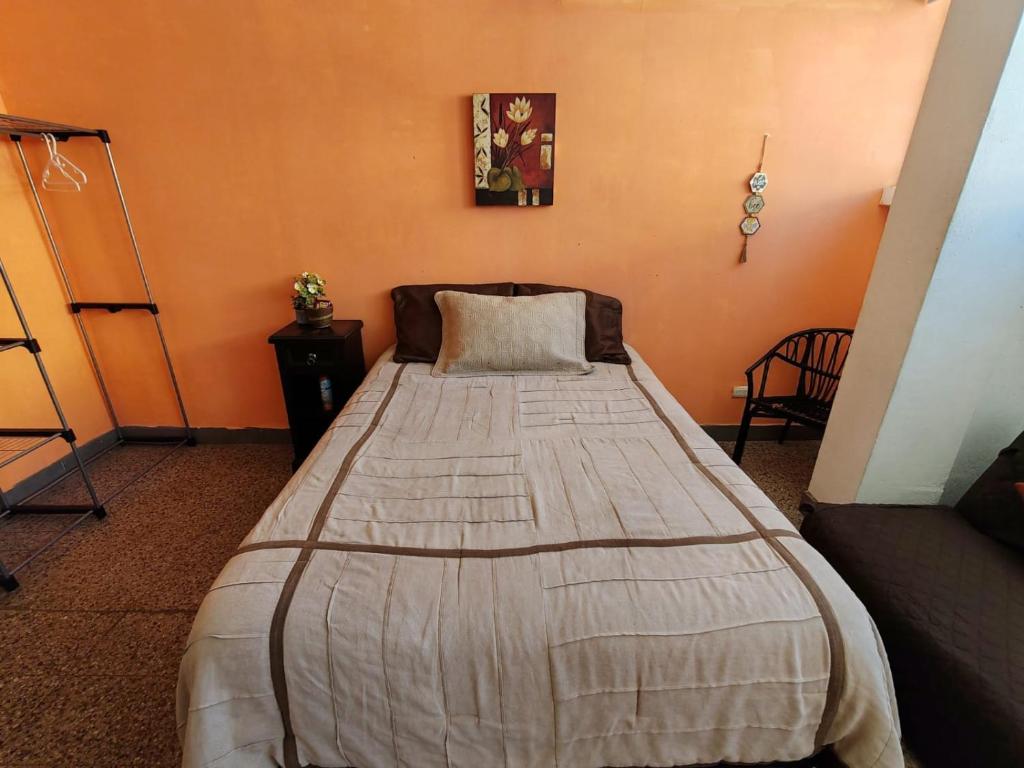 a bed in a room with an orange wall at Apto moderno zona 1 in Guatemala