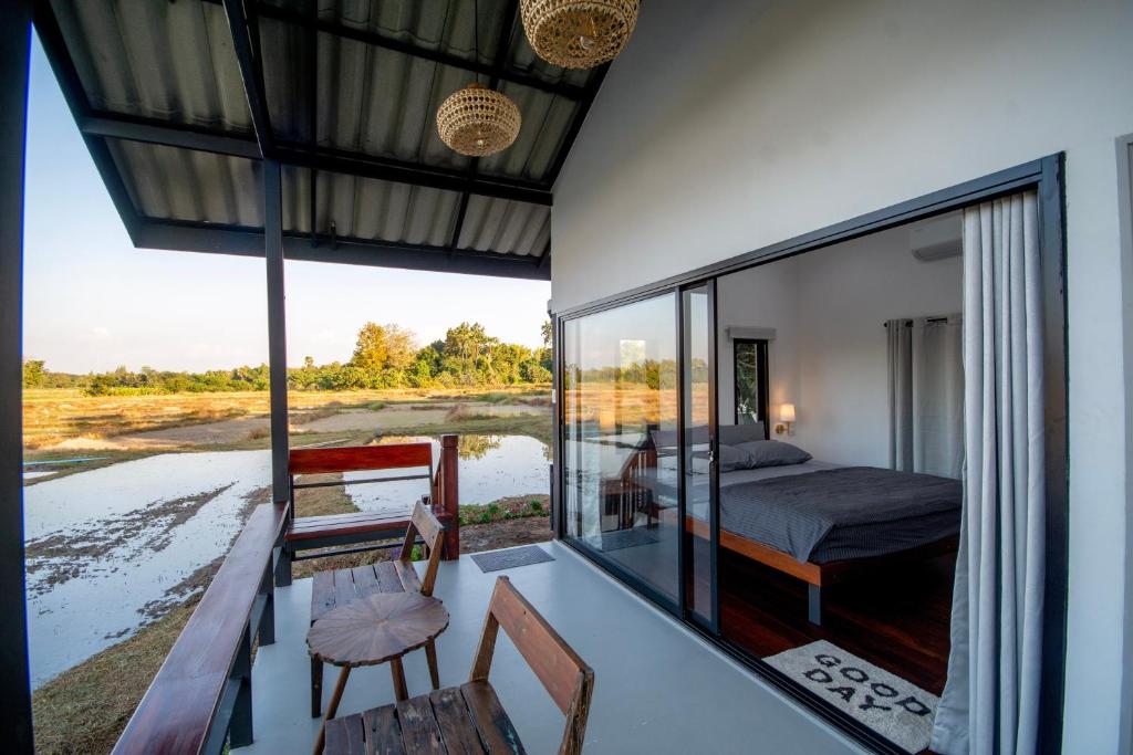 a room with a bed and a view of a river at The Farmer Farm Stay & Cafe in Chom Thong