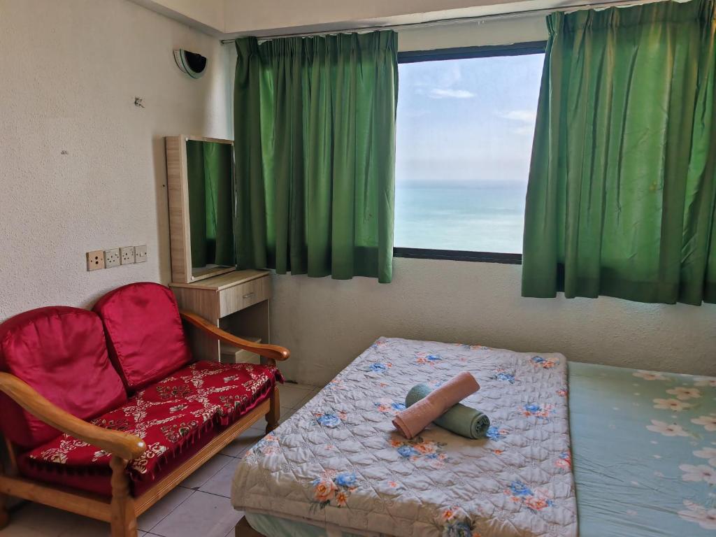 a bedroom with a bed and a chair and a window at Seri Sayang Seaview Resort Batu Ferringhi in Batu Ferringhi