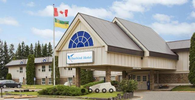 un edificio con una bandera y un coche delante de él en Blue Bird Hotel, en Melfort
