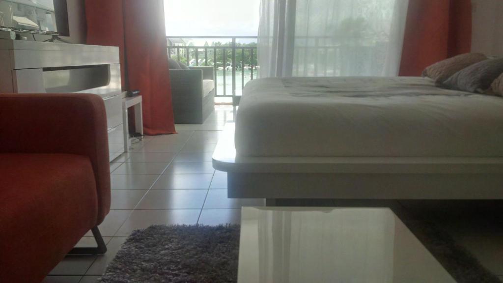 a bedroom with a bed and a view of a balcony at Joli Studio Vue Sur Mer in Pointe-à-Pitre