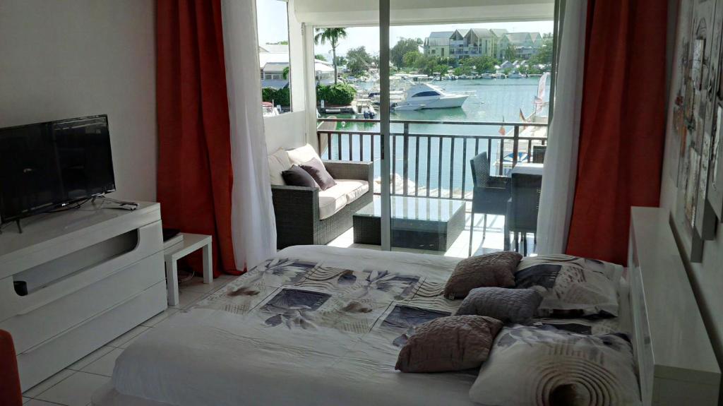 a room with a bed and a television and a balcony at Joli Studio Vue Sur Mer in Pointe-à-Pitre