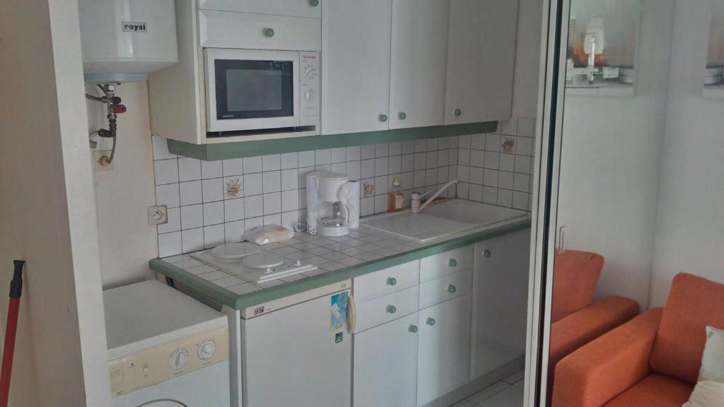a small kitchen with white cabinets and a microwave at Joli Studio Vue Sur Mer in Pointe-à-Pitre
