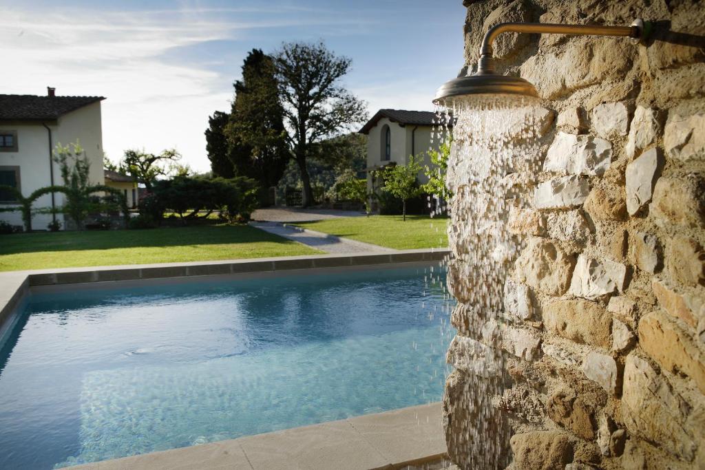 une piscine construite dans un mur en pierre à côté d'une maison dans l'établissement Relais Villa Belpoggio - Residenza D'Epoca, à Loro Ciuffenna