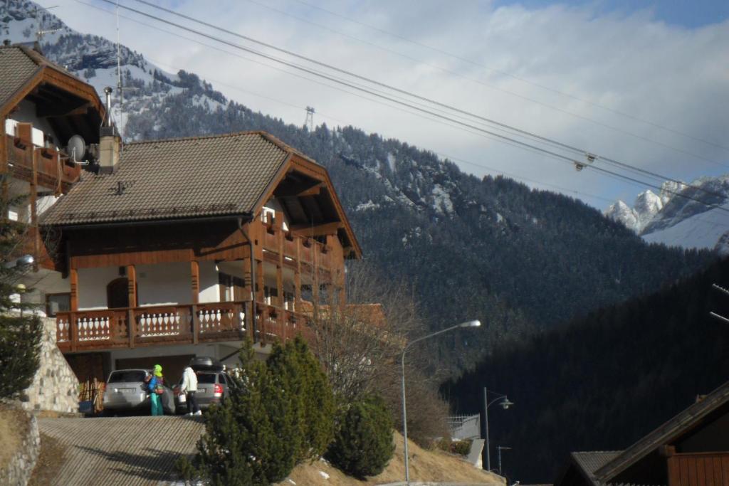 een groot houten huis met bergen op de achtergrond bij Appartamenti Vincenzo E Marcella in Campitello di Fassa