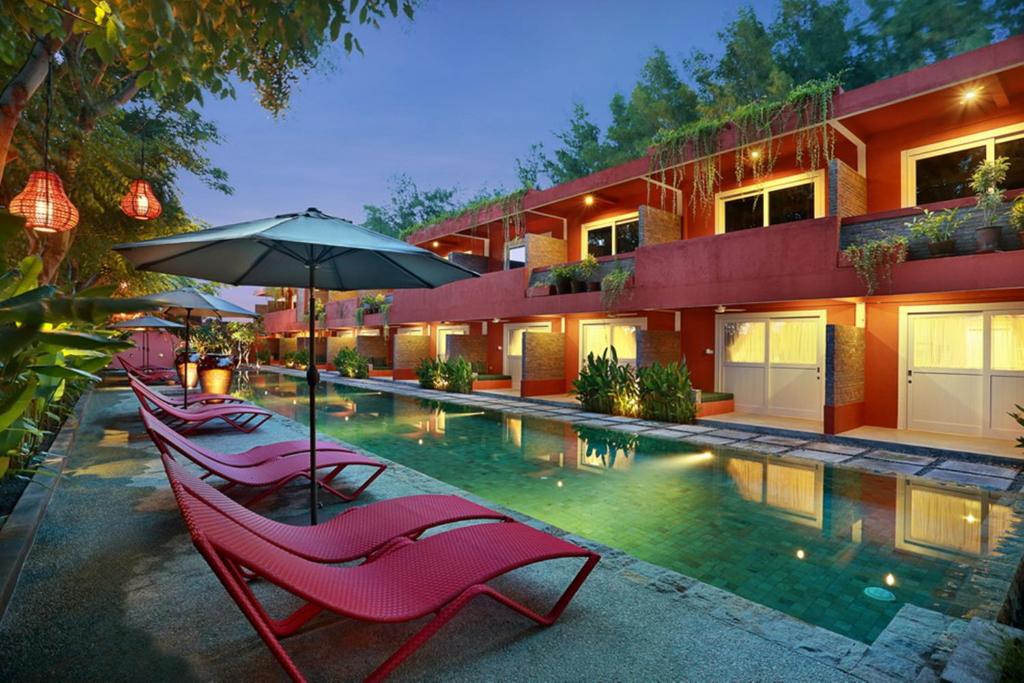 a pool with chairs and an umbrella next to a building at PinkCoco Gili Trawangan - Constant Surprises - for Cool Adults Only in Gili Trawangan