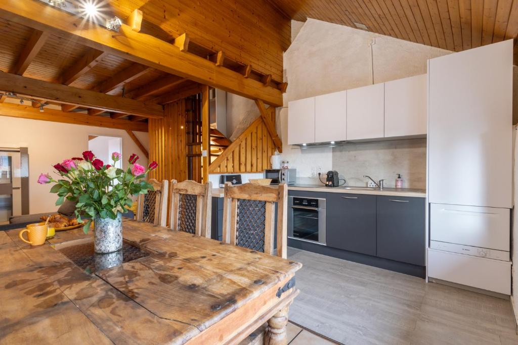 Una cocina con una mesa con un jarrón de flores encima. en Le Refuge proche de Genève, en Viry