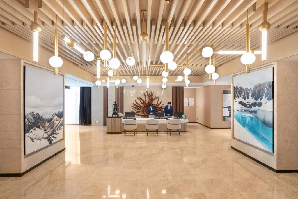 a lobby with tables and chairs in a building at Sha Zhi Ye Serviced Apartment Hotel - Houjie Wanda Plaza Liaoxia Subway Station in Dongguan