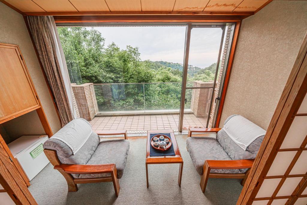 a room with two chairs and a table and a window at 熱海山荘 in Atami