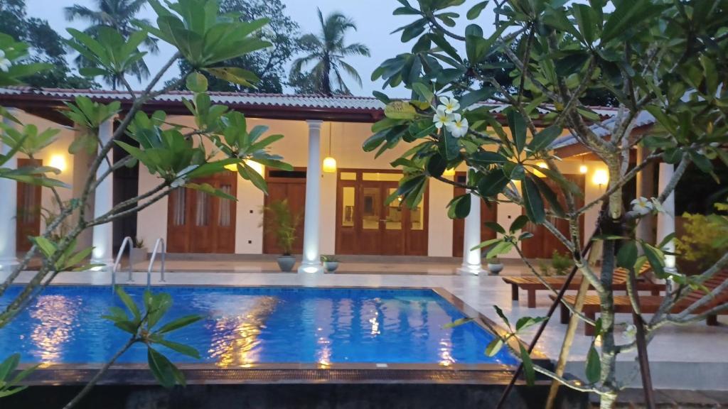 a villa with a swimming pool in front of a house at Summer Heritage Villa in Unawatuna