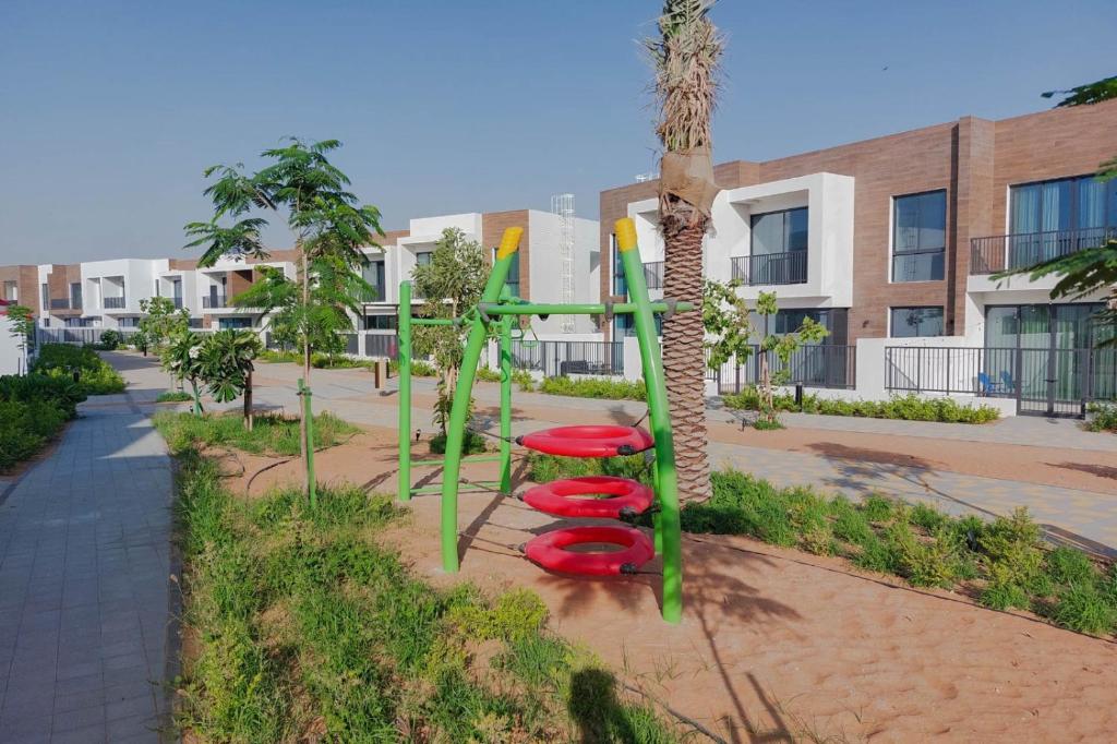 a playground with four red seats next to a palm tree at RAKvista Residence in Ras al Khaimah