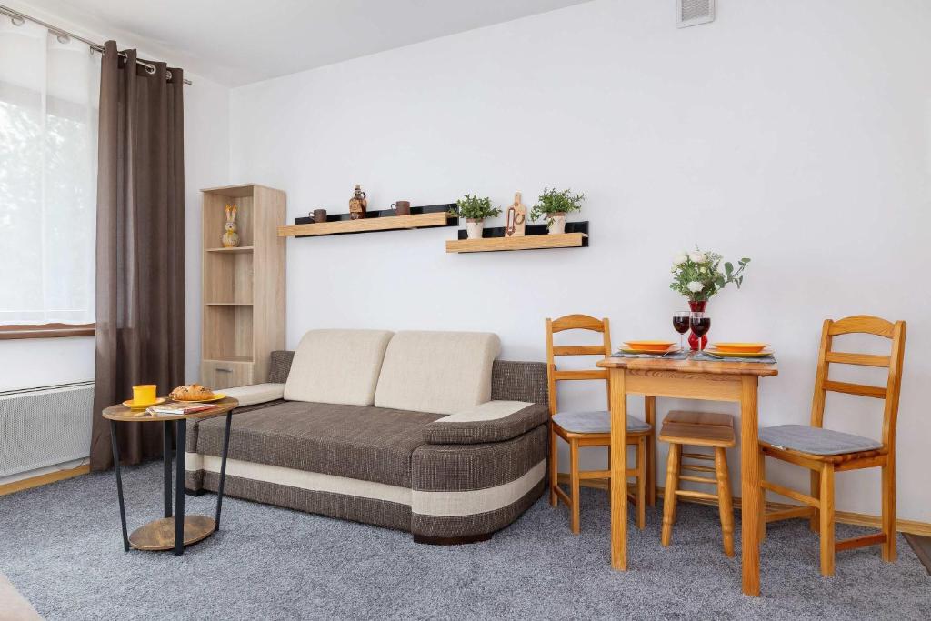 Una sala de estar con un sofá, una mesa y sillas. en Bright Studio with Balcony in Murzasichle by Noclegi Renters, en Murzasichle