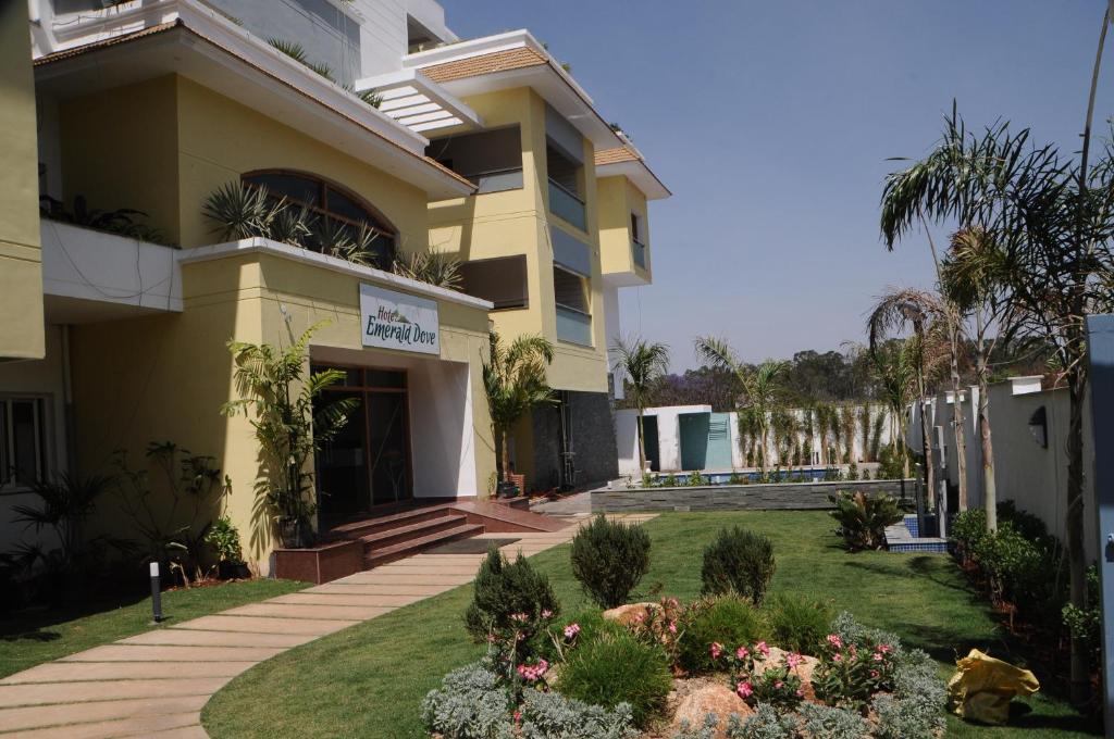 a yellow building with a garden in front of it at Hotel Emerald Dove in Yelagiri