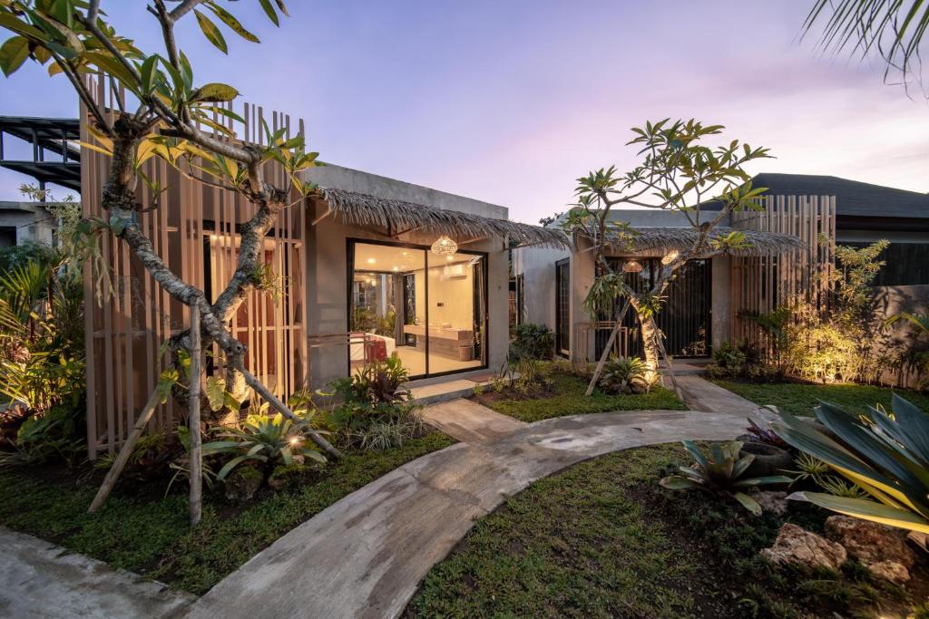 a home with a walkway through a yard with trees at Widji Garden Villa in Uluwatu