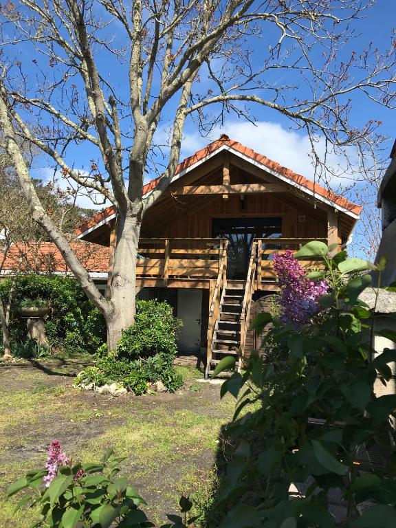 une cabane en rondins avec un arbre et des fleurs dans l'établissement Le Loft, à Lacanau