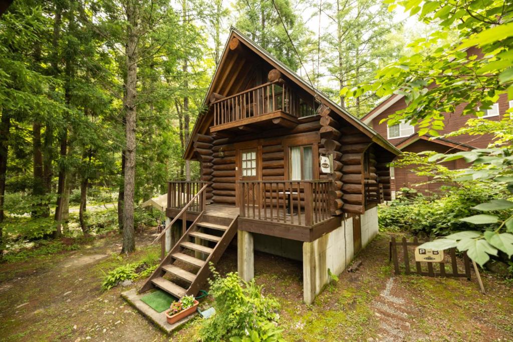 a log cabin in the woods with stairs leading up to it at Reposer Hakuba in Hakuba