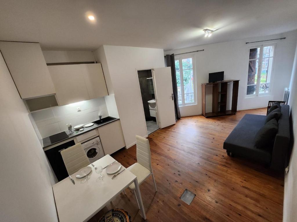 Il dispose d'une cuisine et d'un salon avec une table et un canapé. dans l'établissement Agréable et vaste Studio à 350 M de Paris, à Gentilly