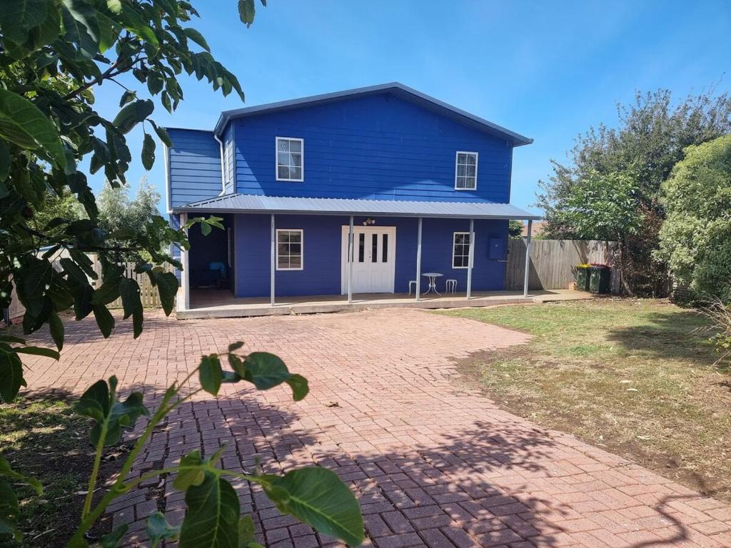 a blue house with a brick driveway in front of it at Blue Waters Swansea Accomodation in Swansea