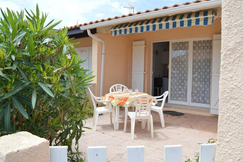 - une table et des chaises sur une terrasse en face d'une maison dans l'établissement Maison 2 pièces mezzanine - Gruissan Ayguades AY110-402, à Narbonne-Plage