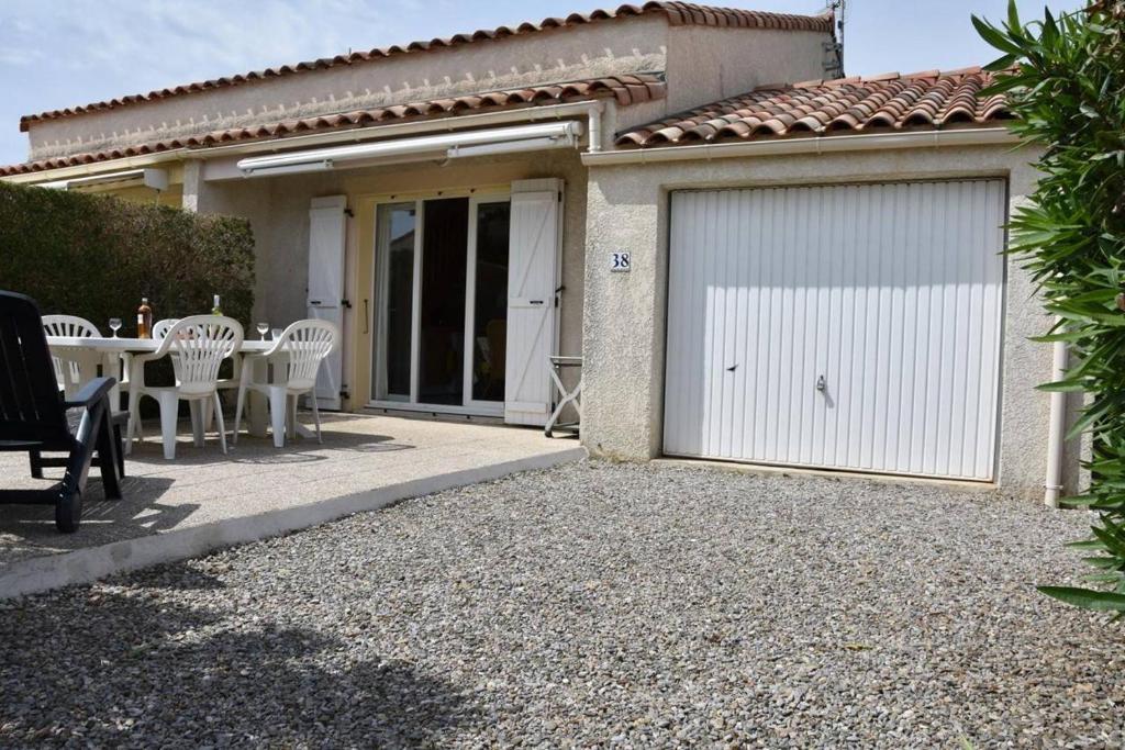 un garage avec une table et des chaises devant une maison dans l'établissement Maison 3 pièces mezzaninne - Gruissan GA120-038, à Gruissan