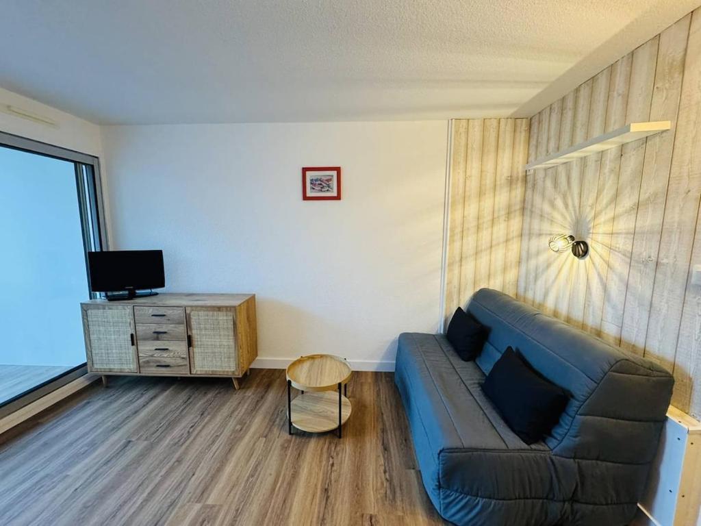 un salon avec un canapé bleu et une télévision dans l'établissement Studio rénové proche plage et commerces, parking, à Quiberon