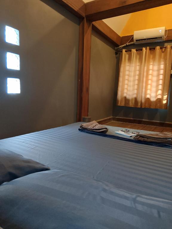 a bedroom with a blue bed with a window at Lazy Bones in Koh Rong Sanloem