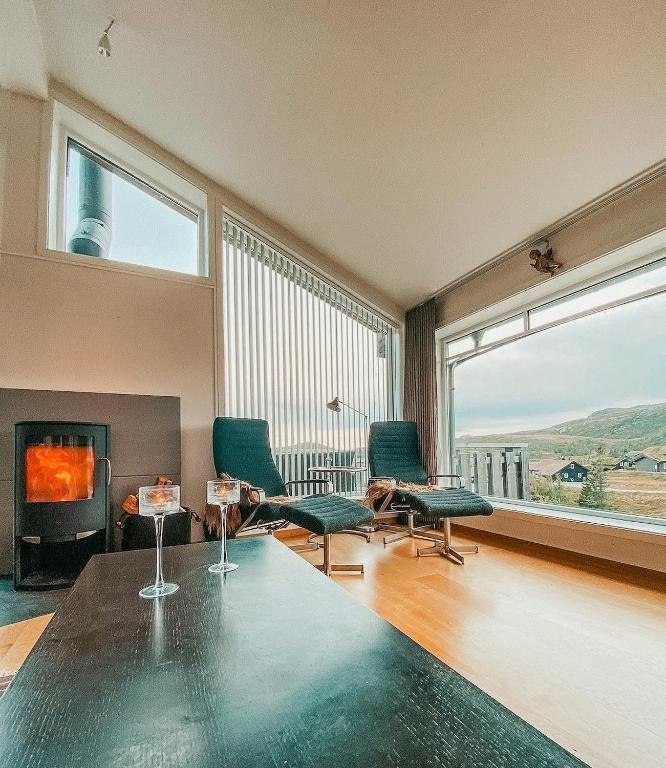 a living room with a table and chairs and a fireplace at Charming Cabin Overlooking Vegglifjell in Kravikfjord