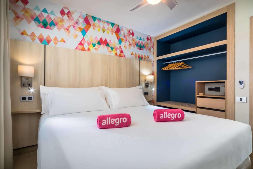 a large white bed with two red pillows on it at Allegro Isora in Puerto de Santiago