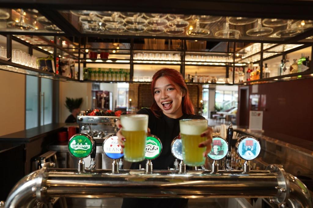 a woman behind a bar with a tray of beers at Wink Hotel Tuy Hoa Beach - 24hrs stay & Rooftop Pool Bar in Tuy Hoa