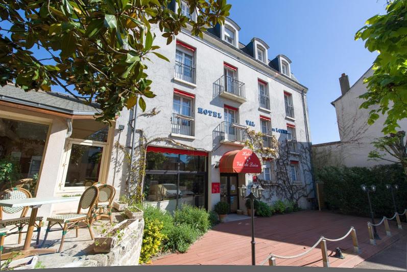 a building with a table and chairs in front of it at Hotel Val De Loire in Azay-le-Rideau