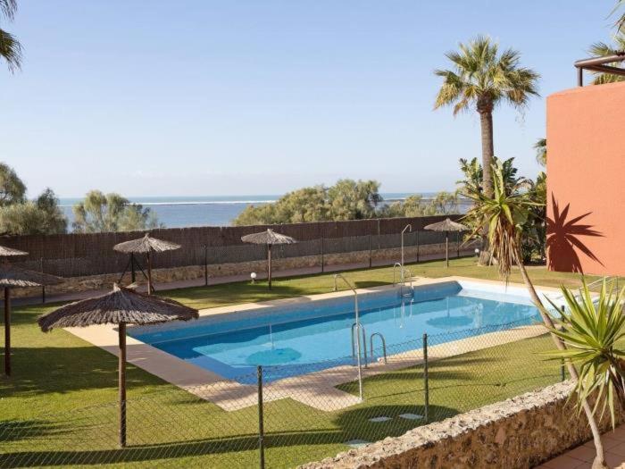 una piscina con sombrillas y el océano en Arrecife Home by Staycare, en Rota