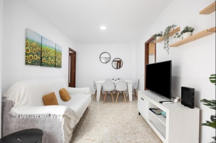 a white living room with a white couch and a tv at Girasoles Rota by Staycare in Rota