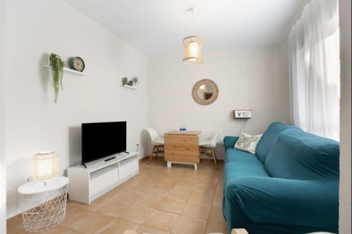 Una sala de estar con un sofá azul y un televisor. en Isaac Peral by Staycare, en Rota