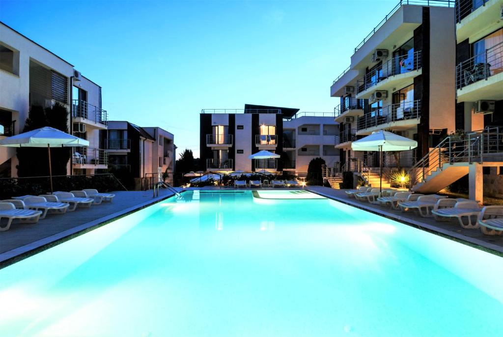 a large swimming pool with chairs and umbrellas at New Line Village Apartments in Sunny Beach