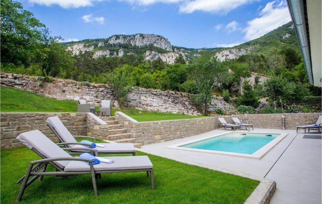 a backyard with a pool and chairs and a rock wall at Villa Orljak in Buzet