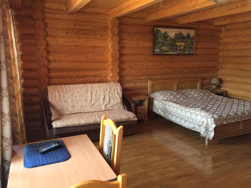 a bedroom with a bed and a chair and a table at Privatna Sadiba Chalet in Oryavchyk