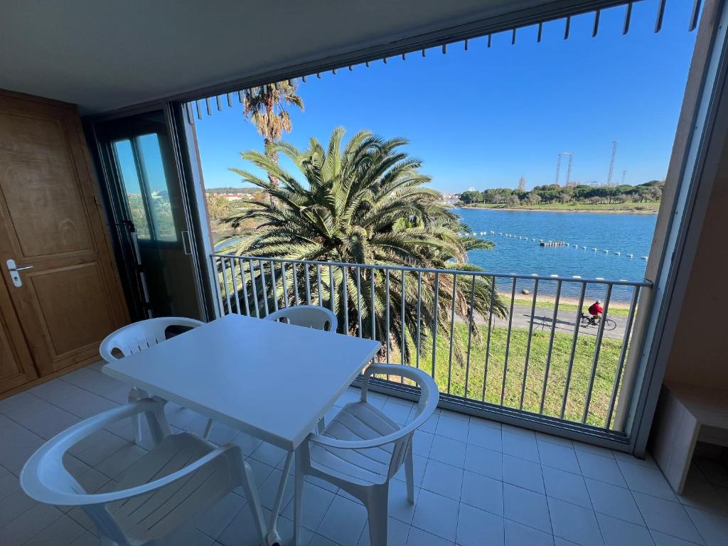 d'un balcon avec une table et des chaises et une vue sur l'eau. dans l'établissement BAIE DES ANGES I Joli T2 cabine piscine proche plage Richelieu Cap d'Agde, au Cap d'Agde