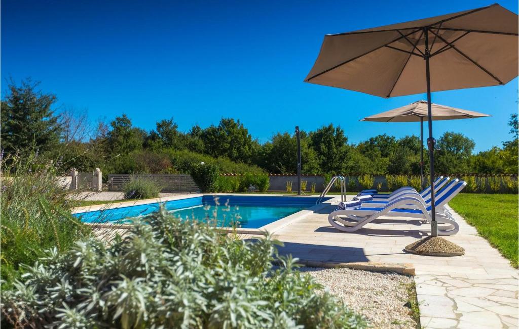 een zwembad met 2 stoelen en een parasol bij Villa Rebici in Pula