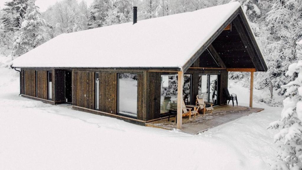 a cabin with a snow covered roof in the snow at Modern Mountain Cabin - Sauna - 5 Bedrooms - Sleeps for 10 in Torpo