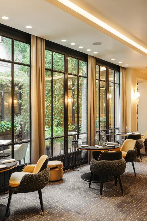 a restaurant with tables and chairs and large windows at Le Burgundy Paris in Paris