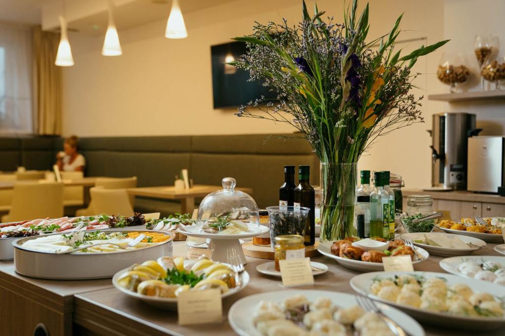 a table with plates of food and a vase of flowers at Hotel Willa Odkrywców in Szklarska Poręba