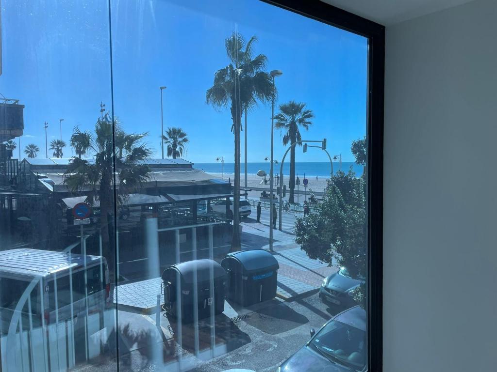 a view of a beach with palm trees and the ocean at Apartamentos Playa Victoria in Cádiz