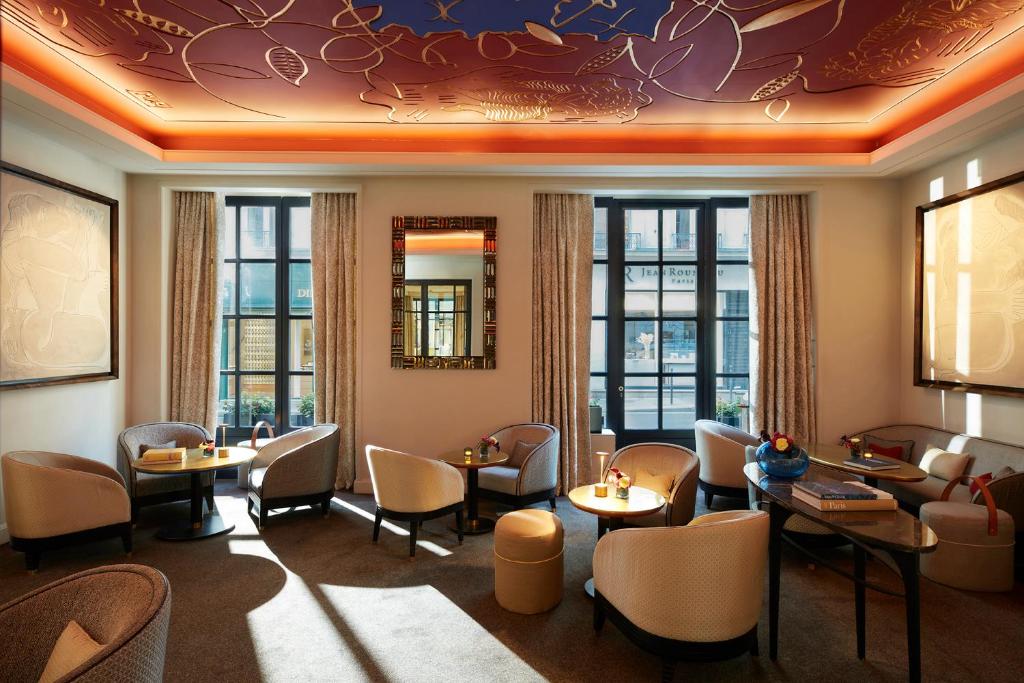 a restaurant with tables and chairs and windows at Le Burgundy Paris in Paris