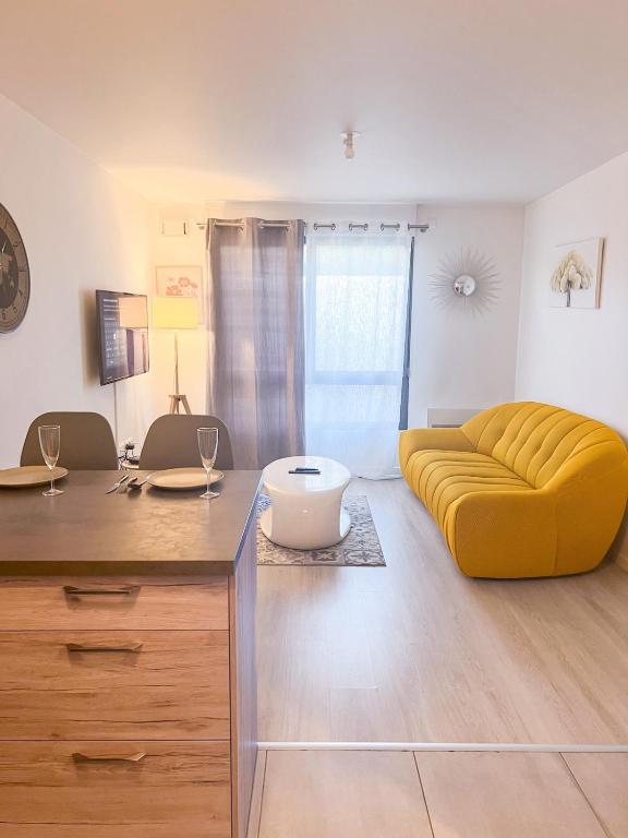 un salon avec un canapé jaune et une table dans l'établissement Sahara - appartement ensoleillé au cœur de Reims, à Reims
